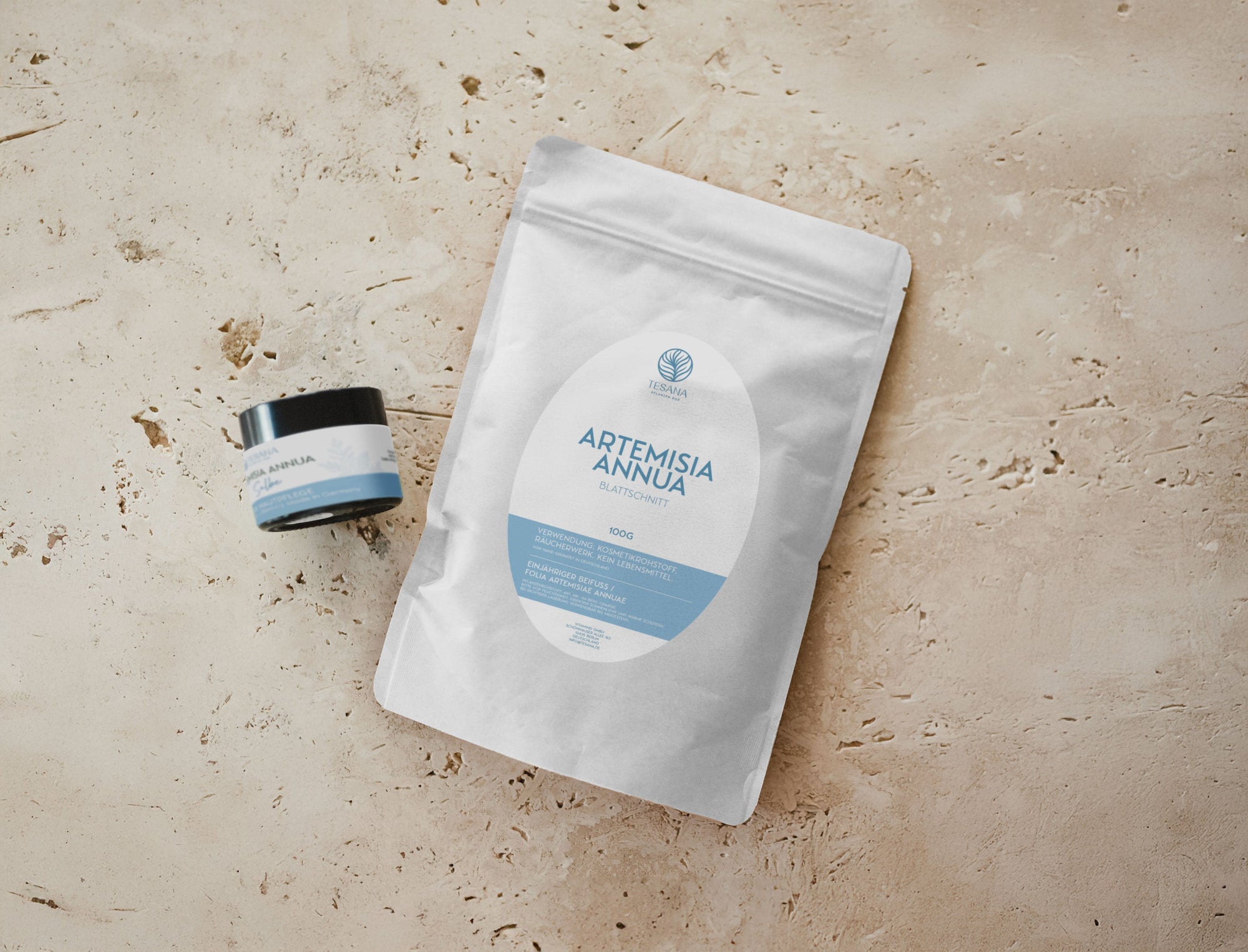 Umweltschonende Verpackungen von Artemisia Annua Produkten. Eine aus Papier, mit Blattschnitt, eine Salbe im braunen Glas.