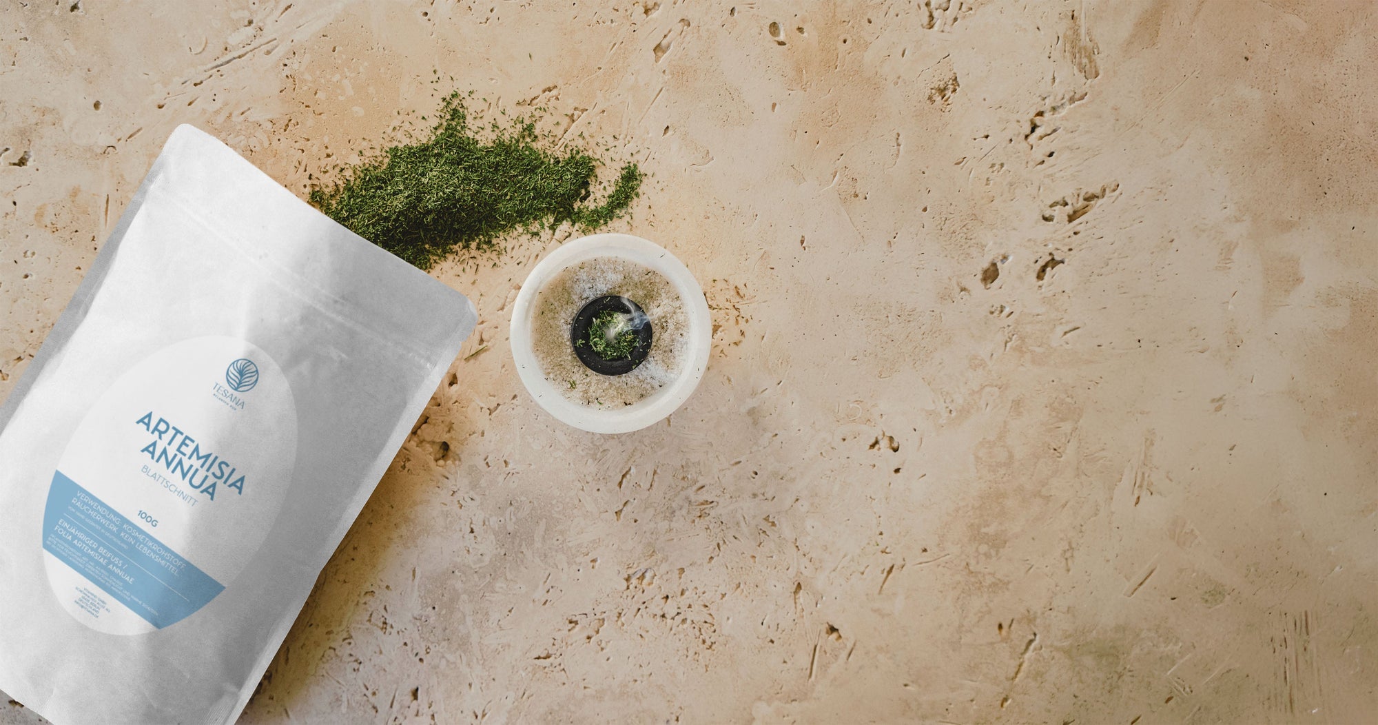 Ein braunes kleines Glas auf hölzerner Oberfläche, umgeben von grünen Pflanzen
